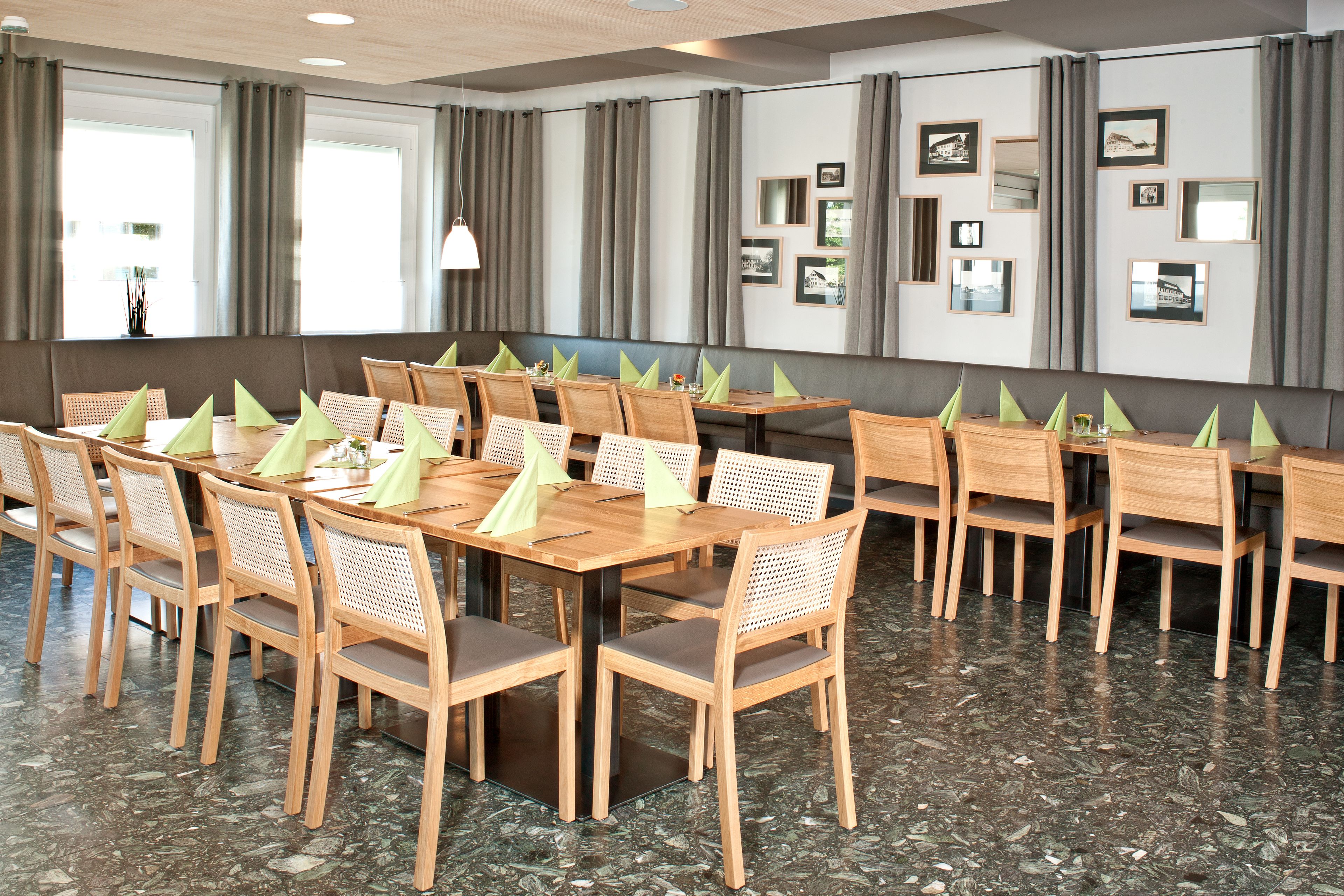 Een vergaderzaal met een lange tafel, meerdere stoelen en foto's in lijsten aan de muren.