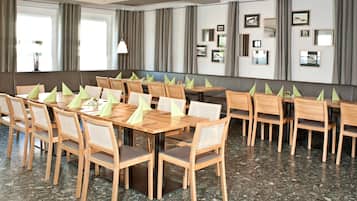 Een vergaderzaal met een lange tafel, meerdere stoelen en foto's in lijsten aan de muren.