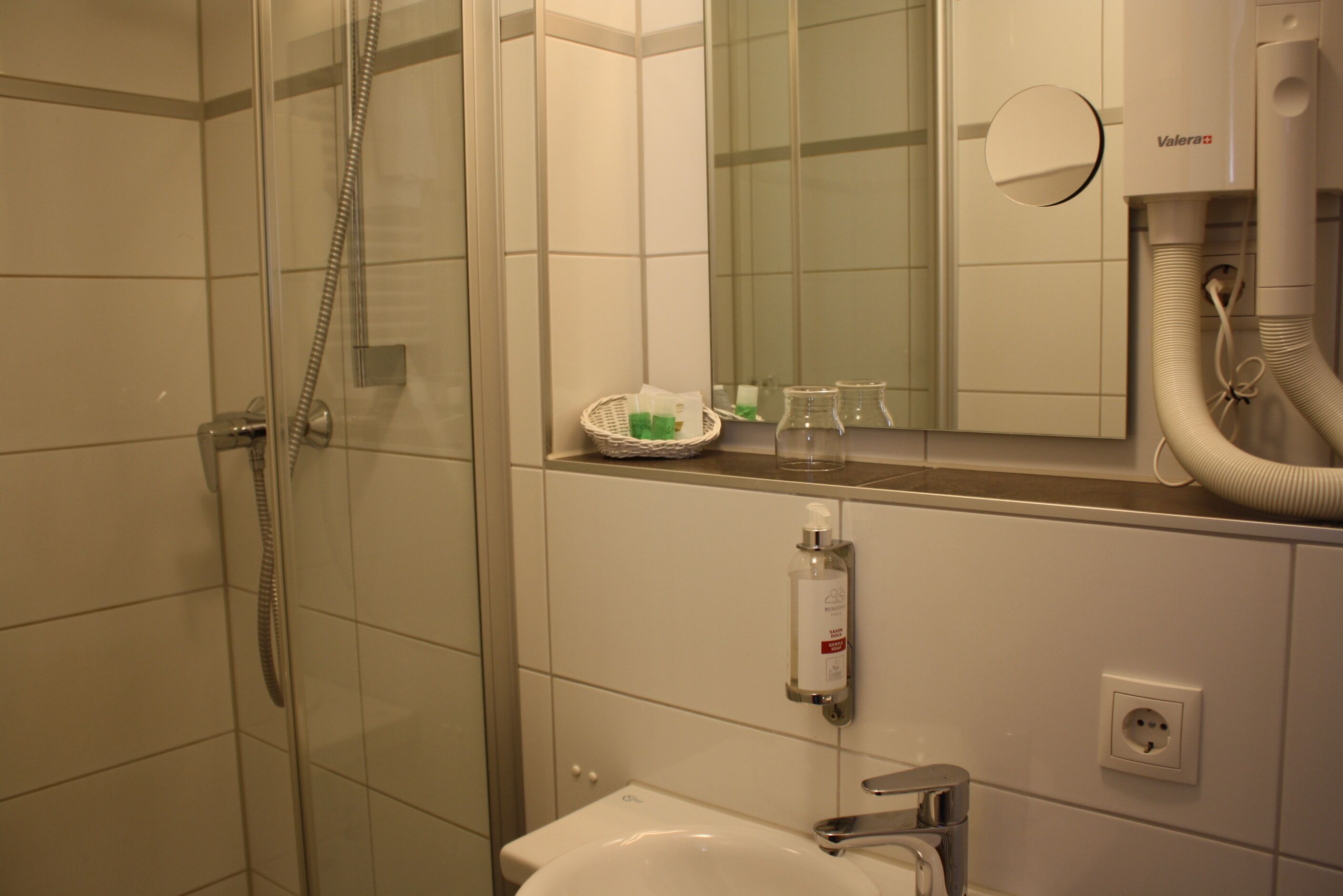 Une salle de bain avec une douche à parois de verre, un lavabo et un miroir.