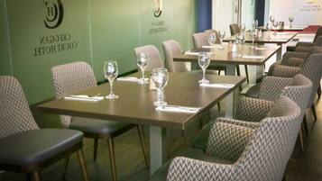 A restaurant with tables set for dining, chairs, and wine glasses.