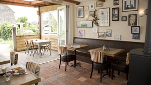 A restaurant with outdoor seating, wooden tables, striped chairs, and a wall adorned with framed pictures. - De Mariahoeve (Terherne)