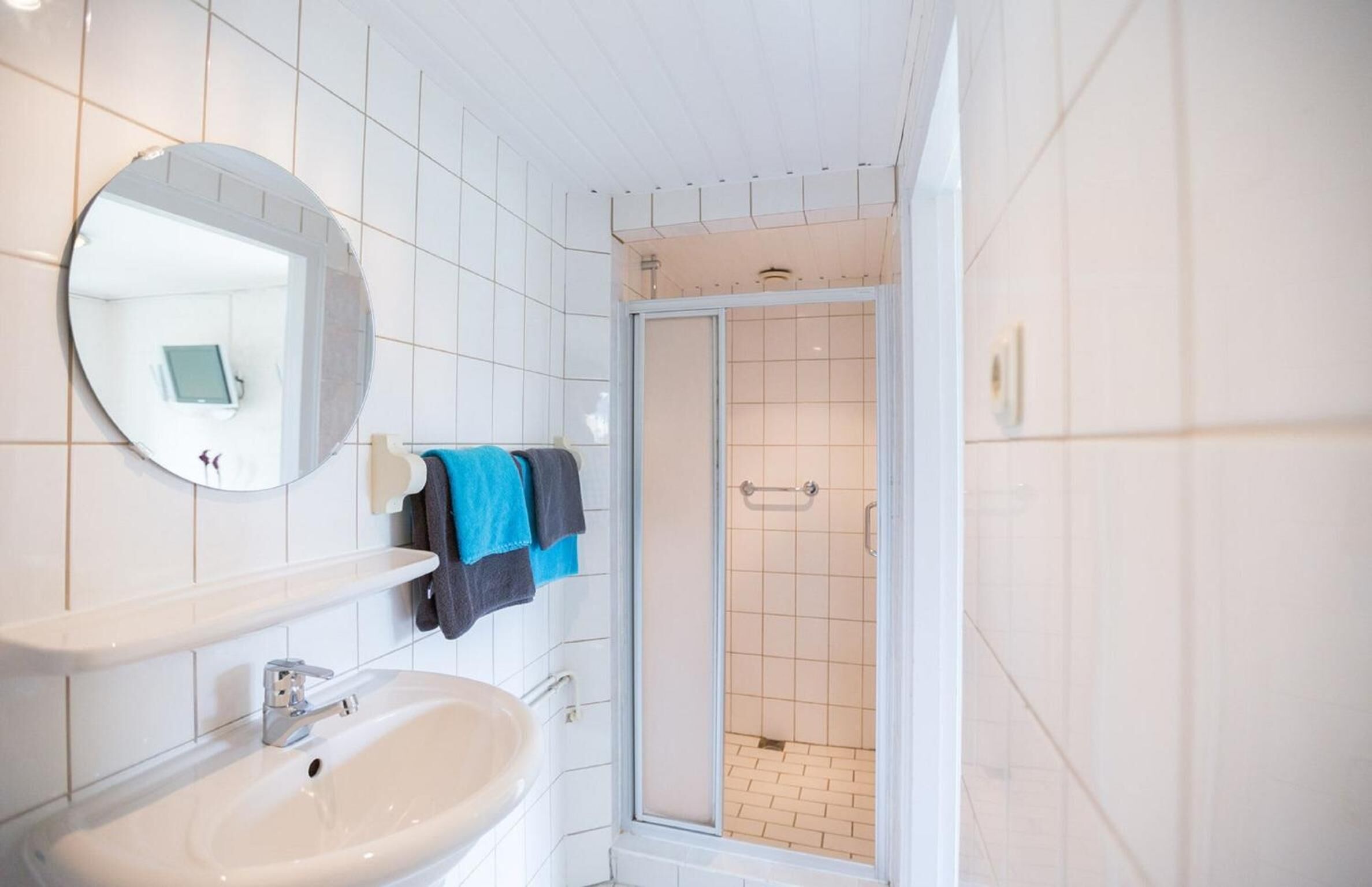 Un bagno con lavandino bianco, specchio e zona doccia.