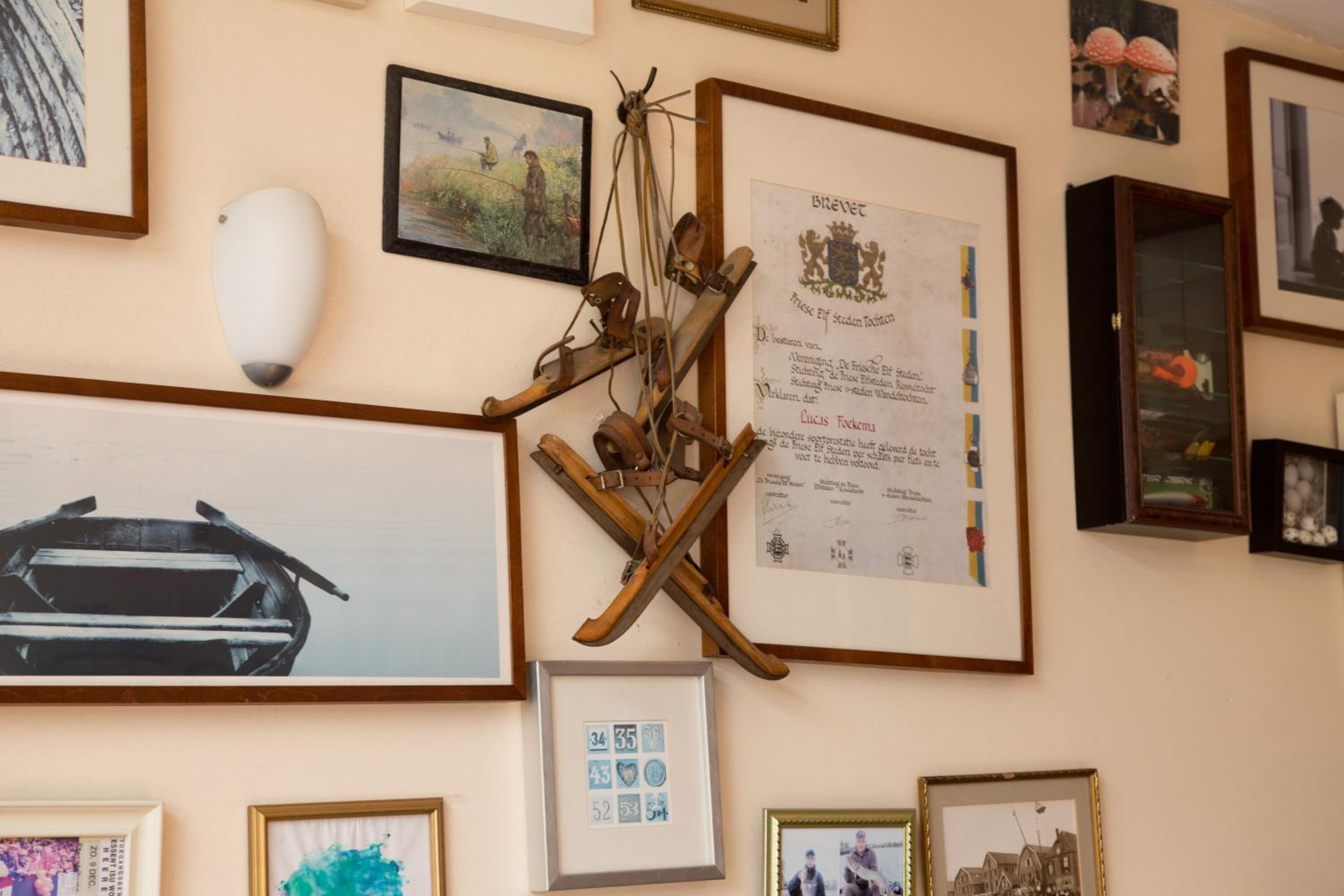 A wall with various framed items including a certificate, photographs, and a decorative wooden structure.