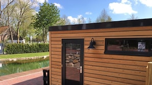 Une cabane en bois avec une porte noire, une fenêtre et un mur de pierre visible à travers la porte.