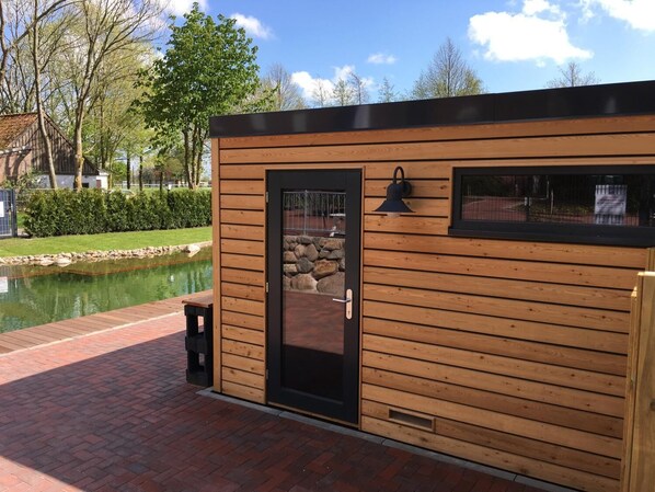 Une cabane en bois avec une porte noire, une fenêtre et un mur de pierre visible à travers la porte.
