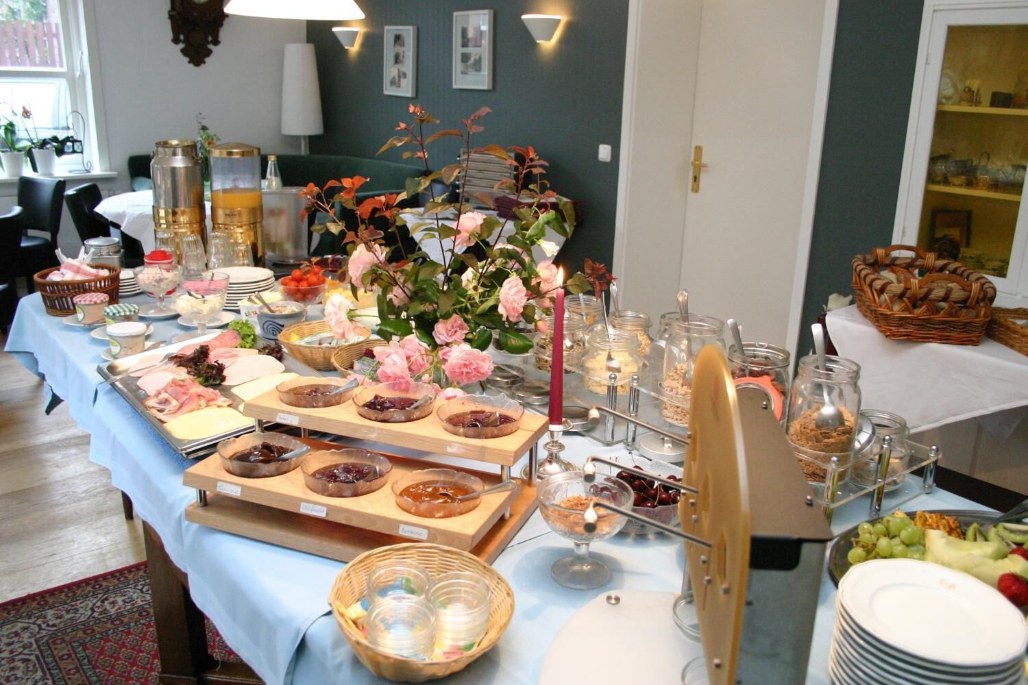 A buffet table with various food items, a vase of flowers, and a candle.