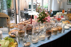 A buffet table with various food items and a vase of flowers. - Gasthof Oldenwöhrden (Woehrden)