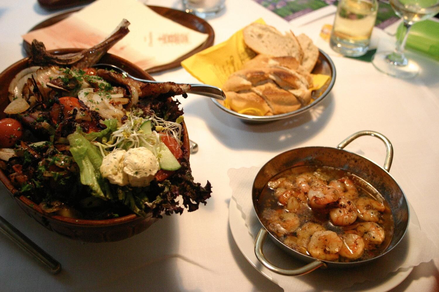 A dining table with a salad, bread, and a seafood dish.