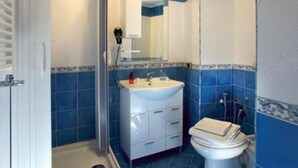 Un baño con lavamanos blanco, inodoro y zona de ducha.