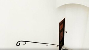 Pared blanca con una puerta de madera y un tirador metálico.