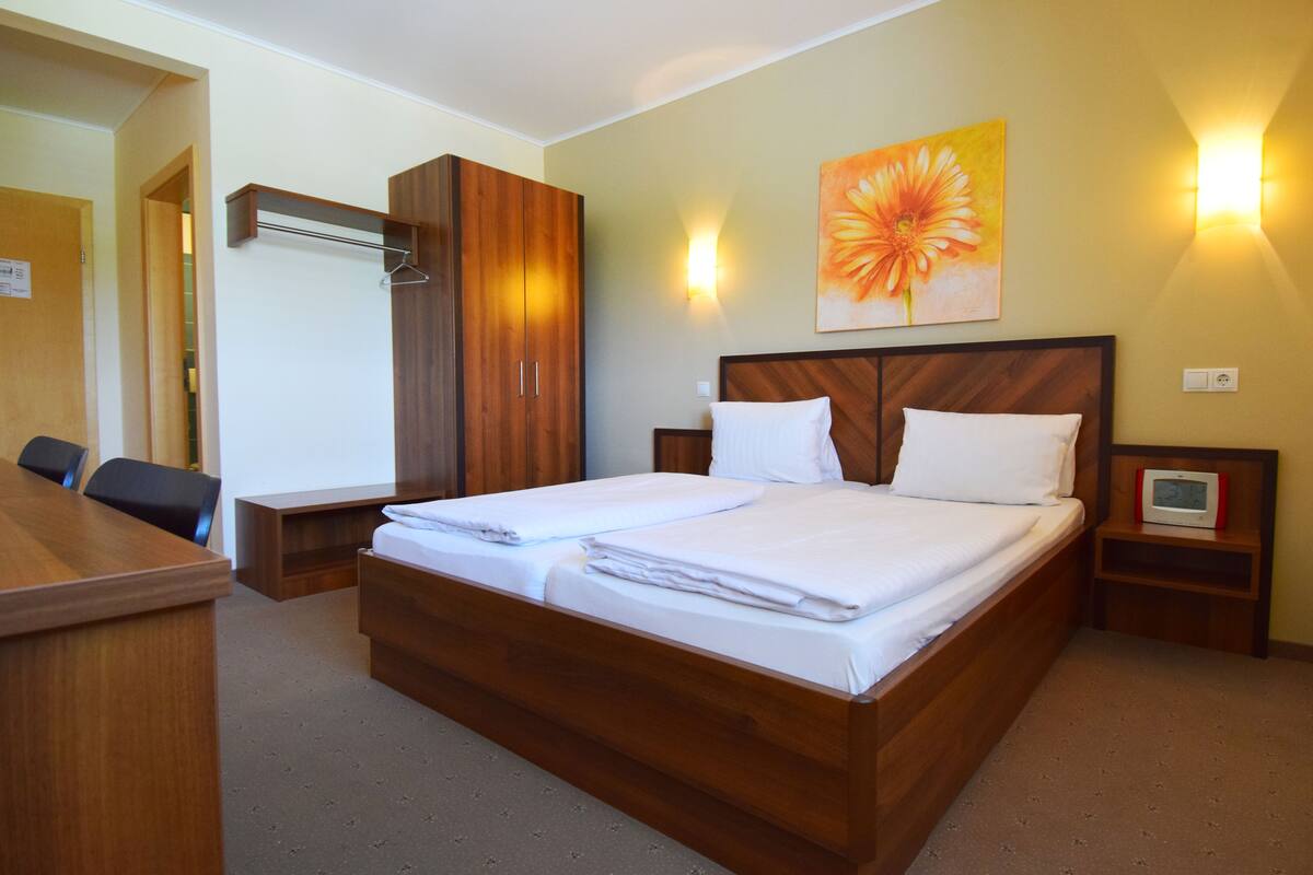Quarto de hotel com cama de madeira, escrivaninha e cadeira.