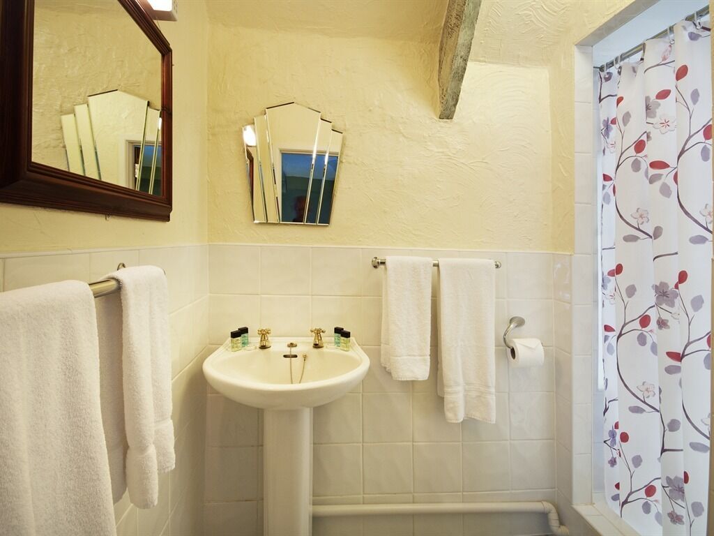 Un baño con lavamanos, dos espejos y cortina de ducha con estampado floral.