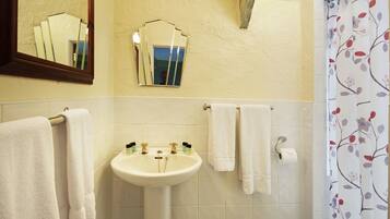 Un baño con lavamanos, dos espejos y cortina de ducha con estampado floral.