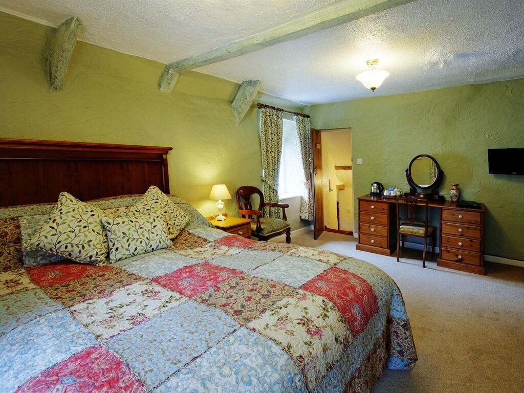 A bedroom with a large bed, a dresser, a chair, and a desk.