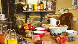 A breakfast buffet with various fruits, cereals, and a pitcher of orange juice. - Tinhay Mill Guest House (Lifton)