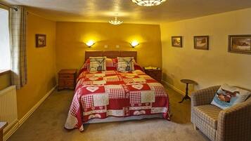 Un dormitorio con una cama grande, dos mesitas de noche, una silla y una pequeña mesa.