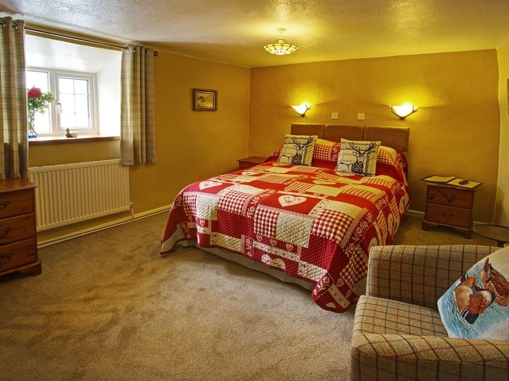 A bedroom with a large bed, two bedside tables, a dresser, and a window with curtains.