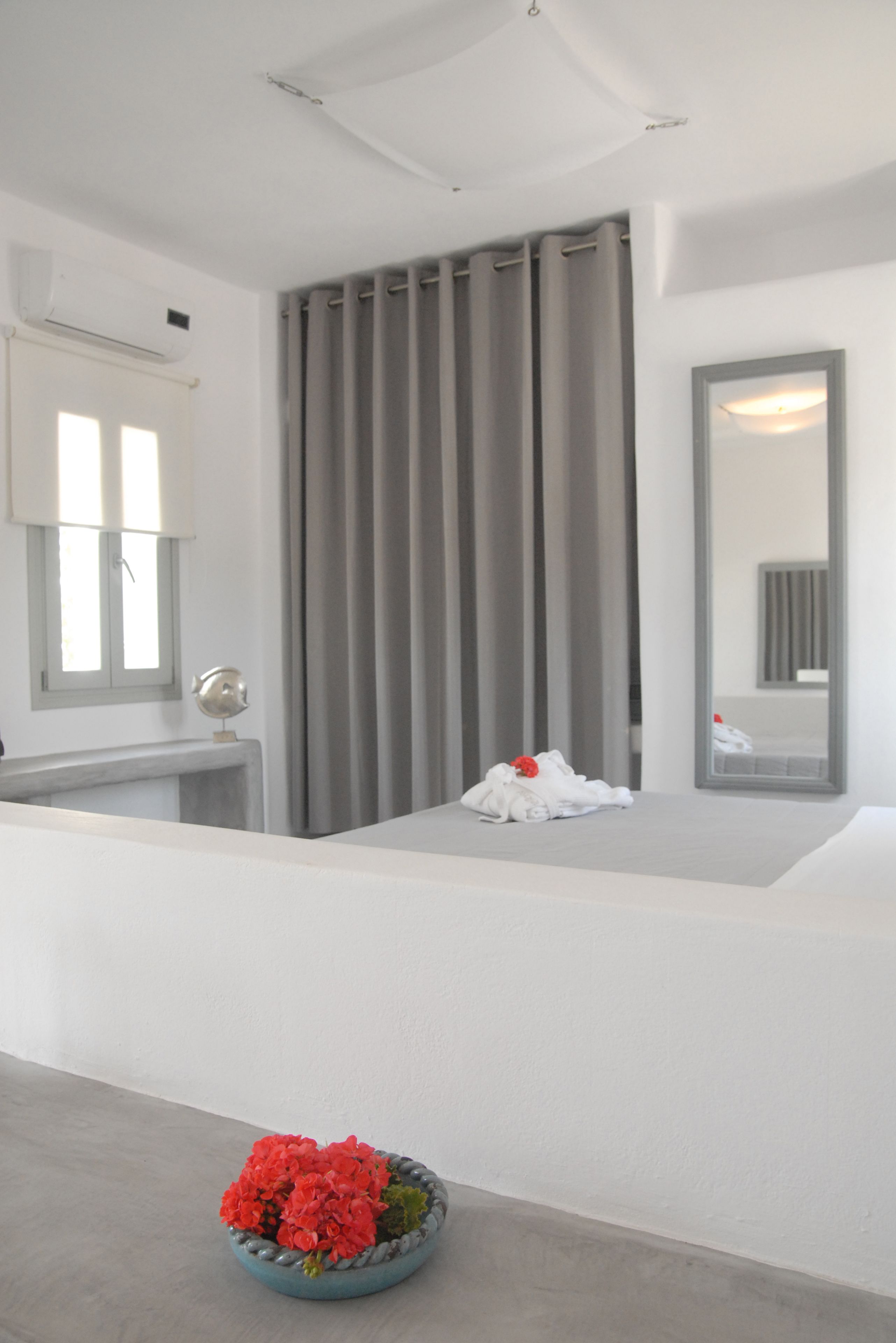 A modern bathroom with a white vanity, a mirror, and a window with curtains.
