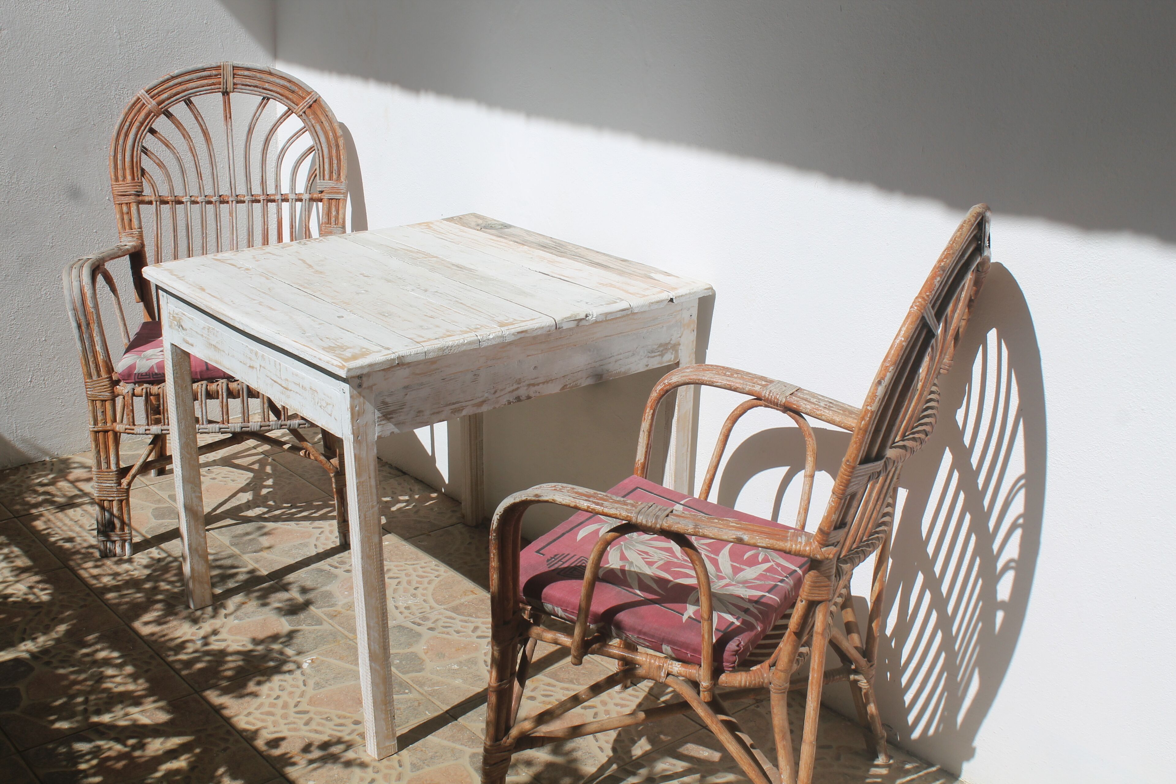 Een klein terras met een tafel en twee rieten stoelen.