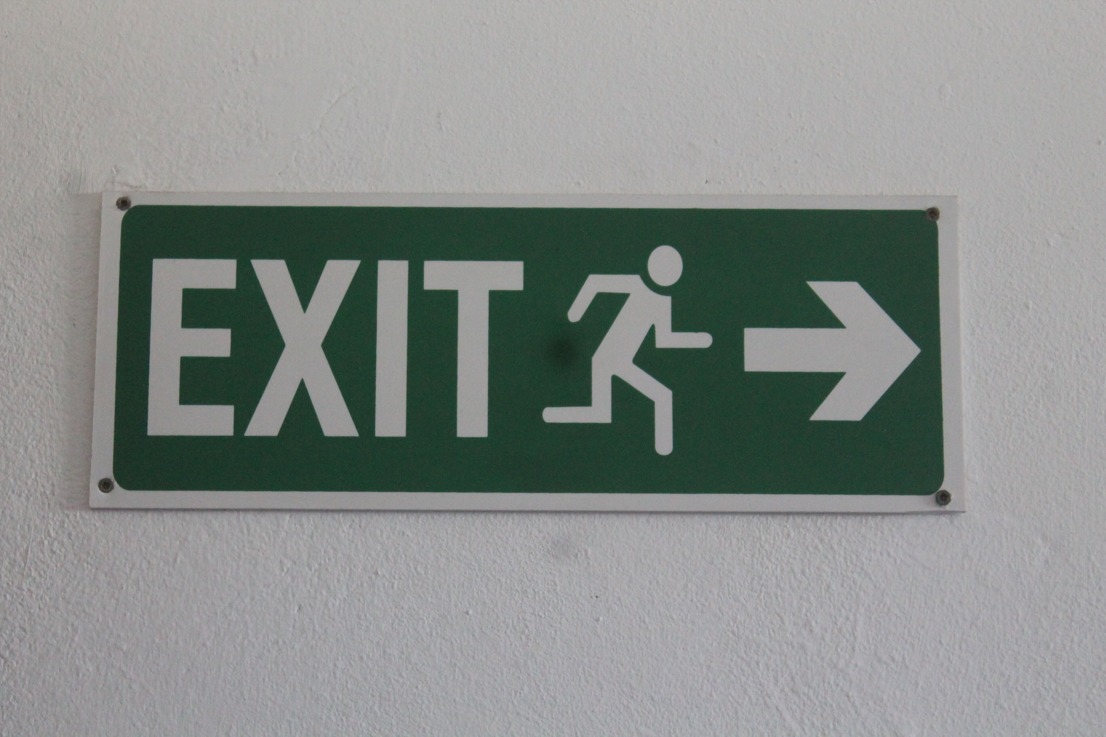 A green EXIT sign with a white running figure and an arrow pointing to the right.