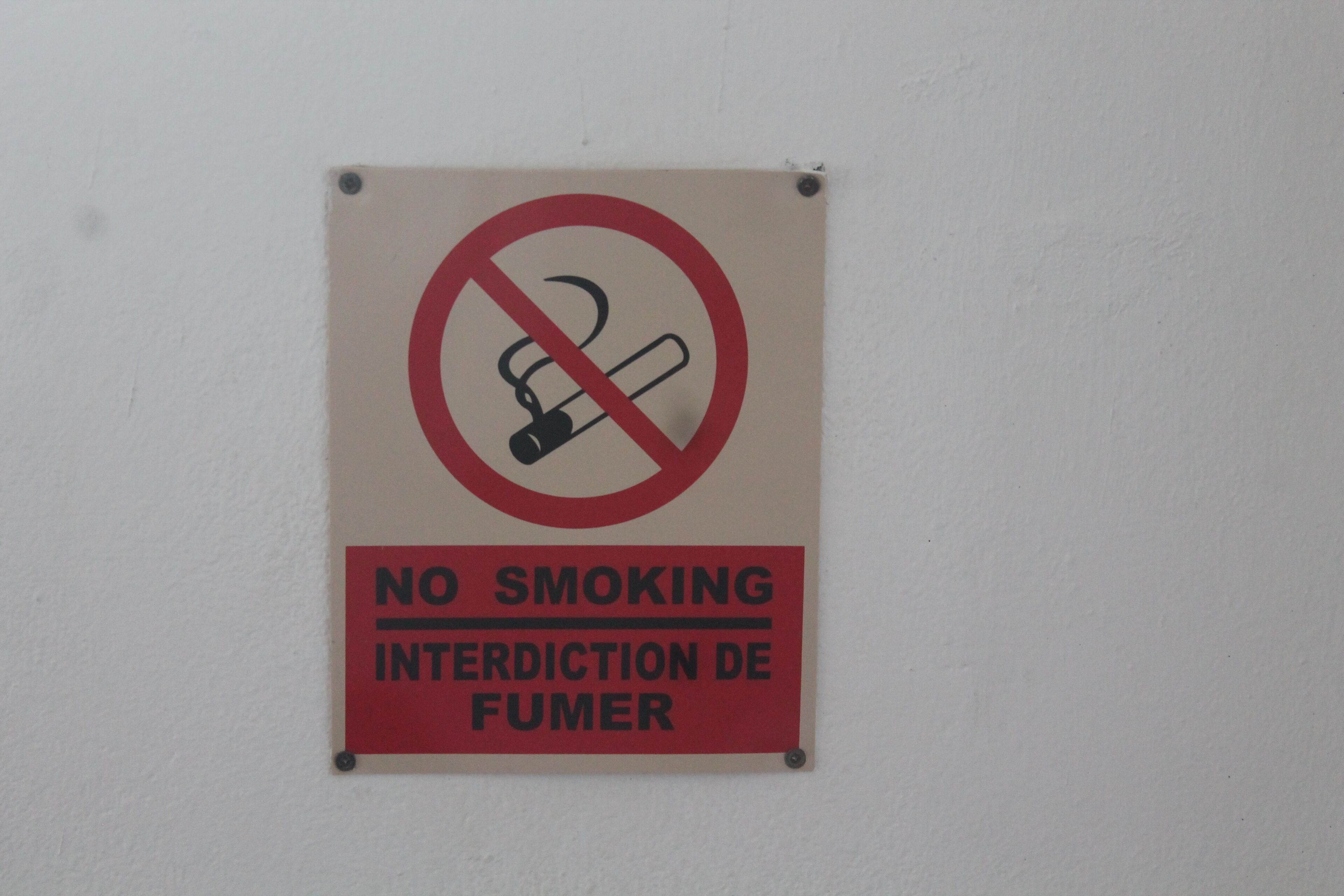 A no smoking sign with text in English and French.
