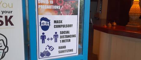 Letrero sobre precauciones por COVID-19, que indica la obligatoriedad del uso de mascarilla, el distanciamiento social y la desinfección de manos.