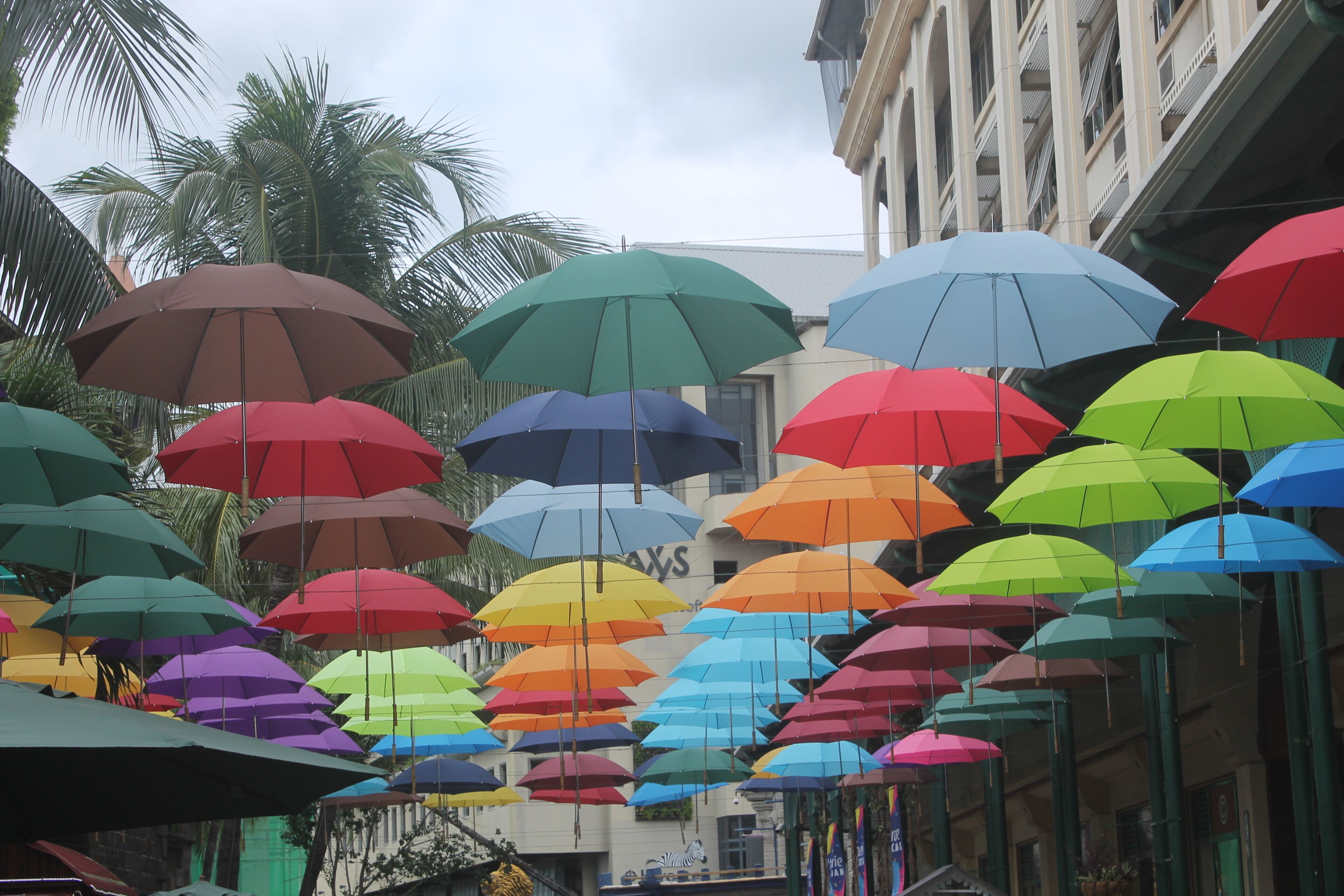 A street with colorful umbrellas hanging overhead.