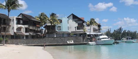 Una propiedad frente al mar con varias edificaciones, una playa de arena y barcos amarrados cerca del agua.