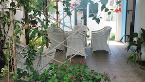 A covered outdoor seating area with wicker furniture and potted plants. - Auberge Miko (Grand-Baie)
