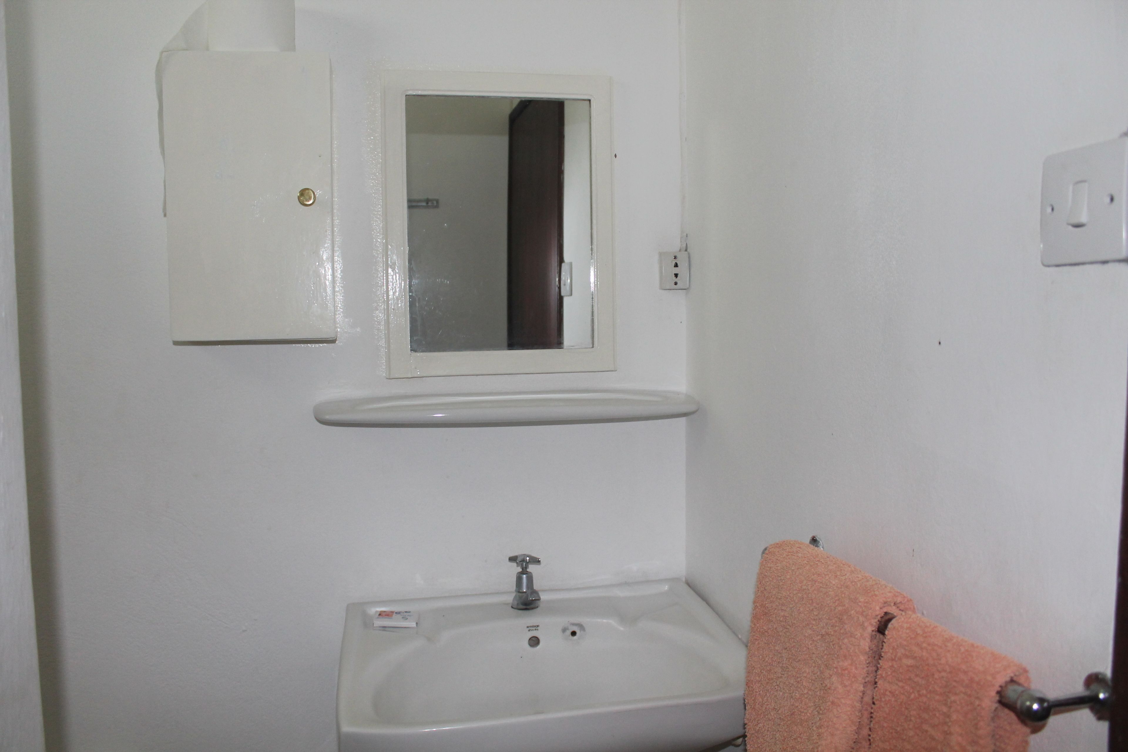 A bathroom with a white sink, a mirror, and a towel hanging on a rack.
