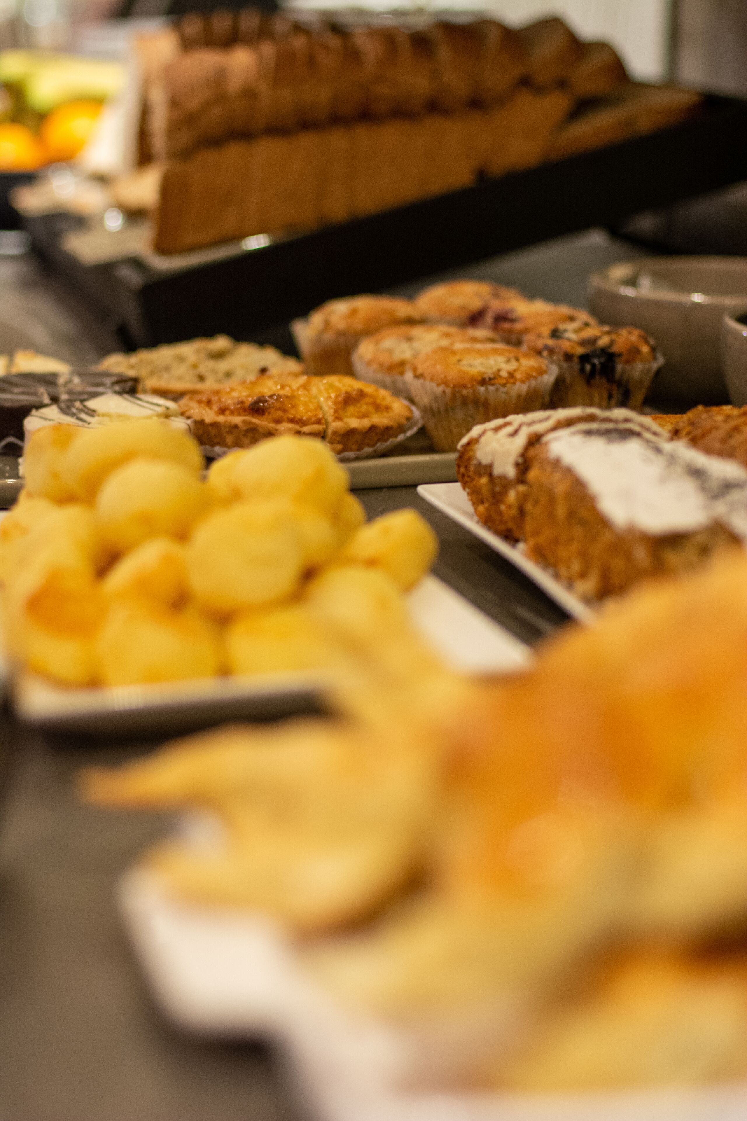 Una mesa de buffet con diversos productos de panadería, como muffins, pasteles y pan.