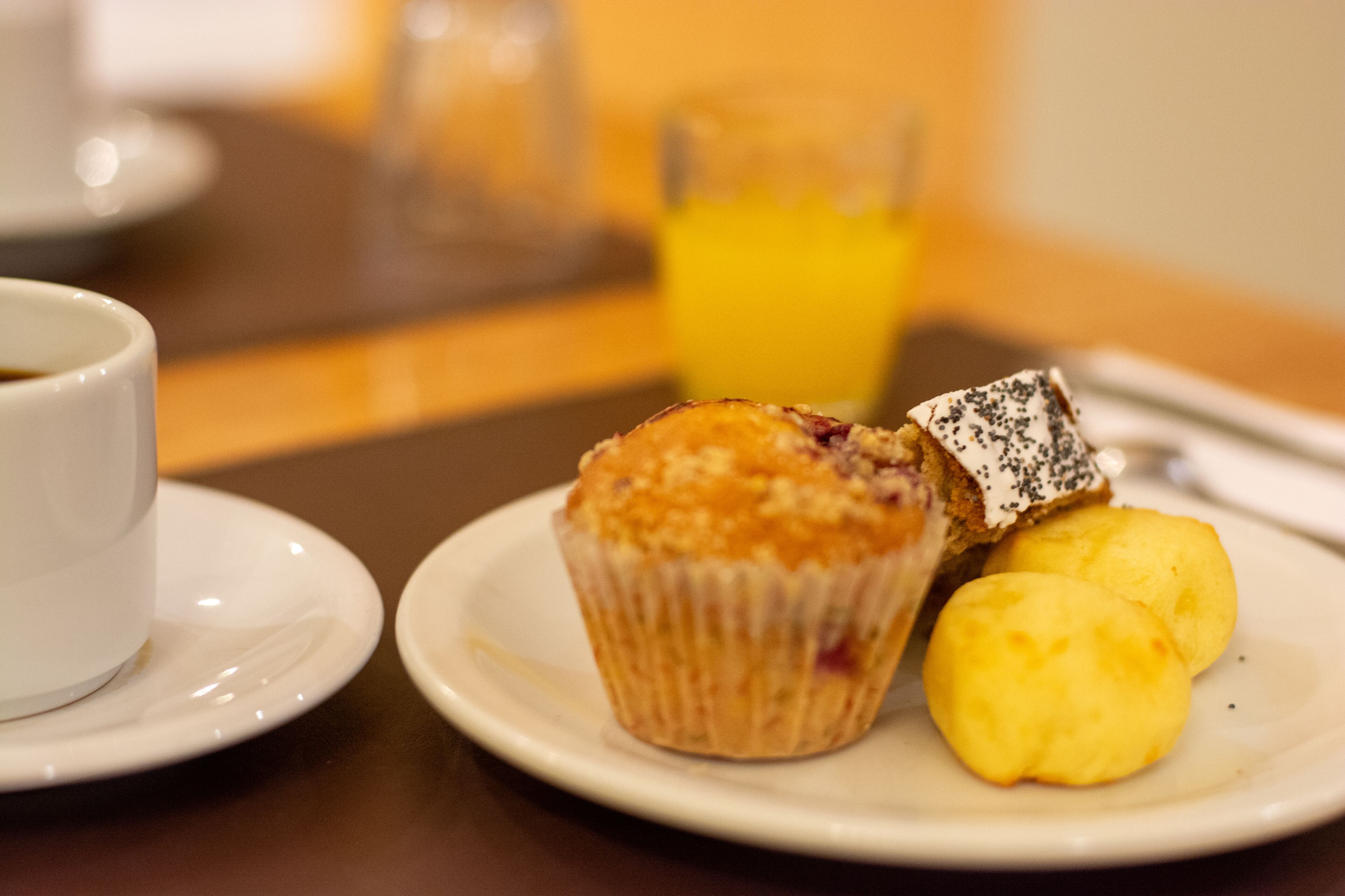 A breakfast setting with a muffin, two biscuits, and a cup of coffee on a white plate.
