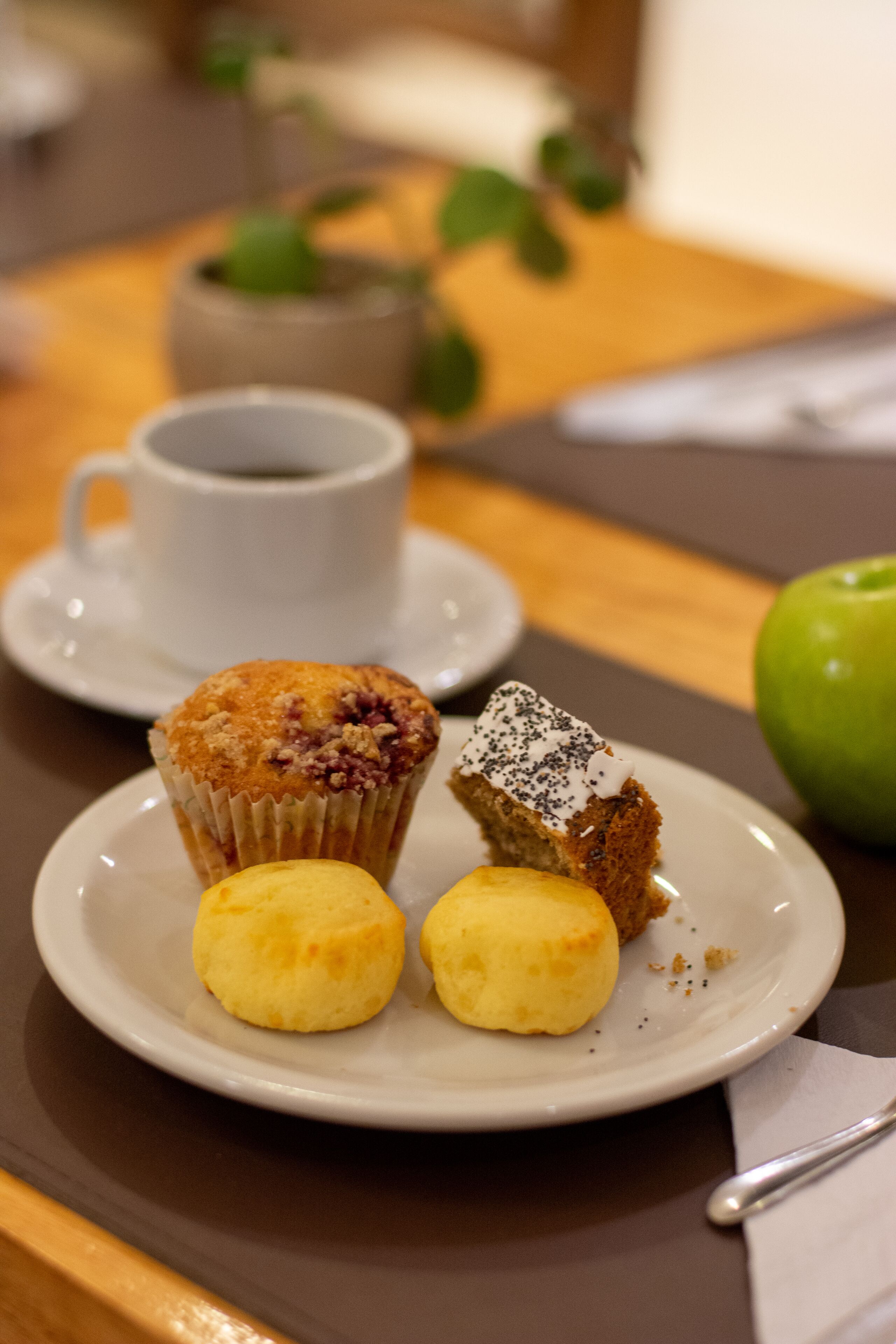 A plate with a muffin, two small buns, and a piece of cake on a table.