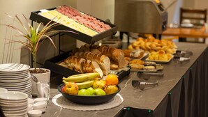 Un buffet proposant une variété d’aliments, notamment des fruits, du pain et de la viande.