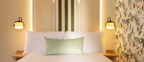 A hotel room with a bed, two bedside lamps, and a floral wallpaper.