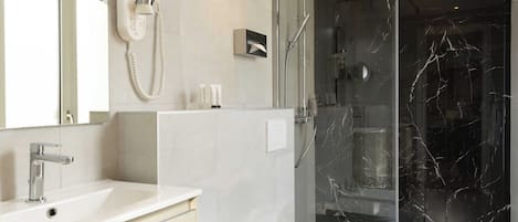 A modern bathroom with a glass-enclosed shower, a white sink, and a toilet.