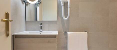 A modern bathroom with a sink, mirror, towel rack, and a hairdryer.