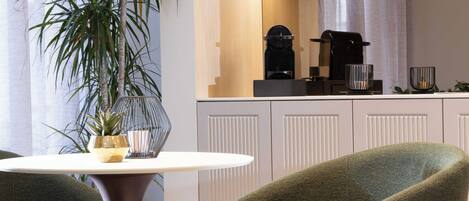 A modern kitchen with white cabinetry, a dining table with chairs, and a potted plant.