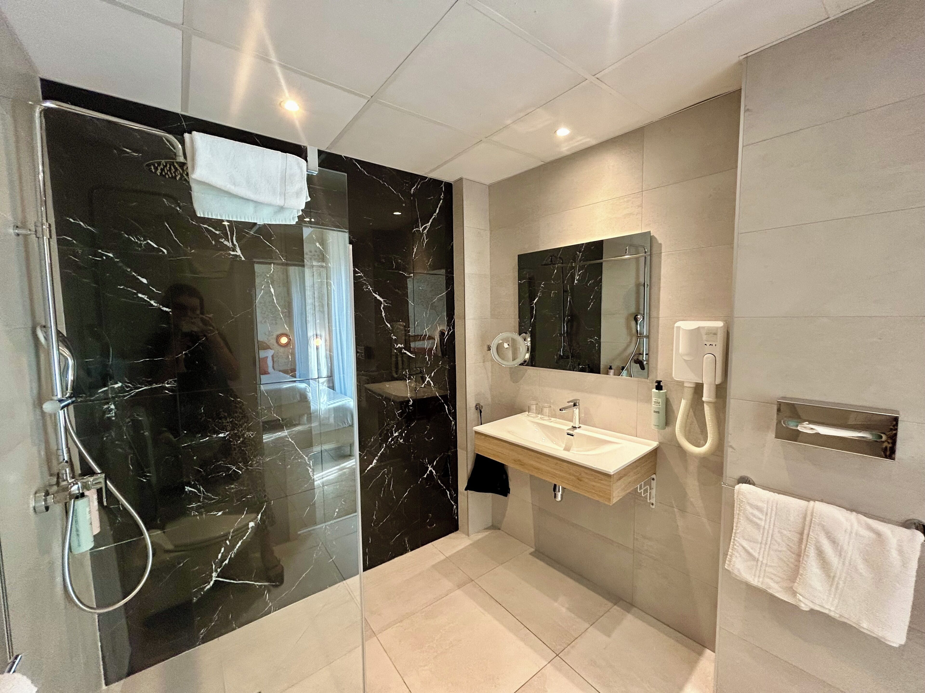 Une salle de bain moderne avec une douche à parois de verre, un meuble-lavabo avec un miroir et un porte-serviettes.