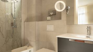 A modern bathroom with a glass-enclosed shower, a white toilet, a vanity with a mirror, and a sink.