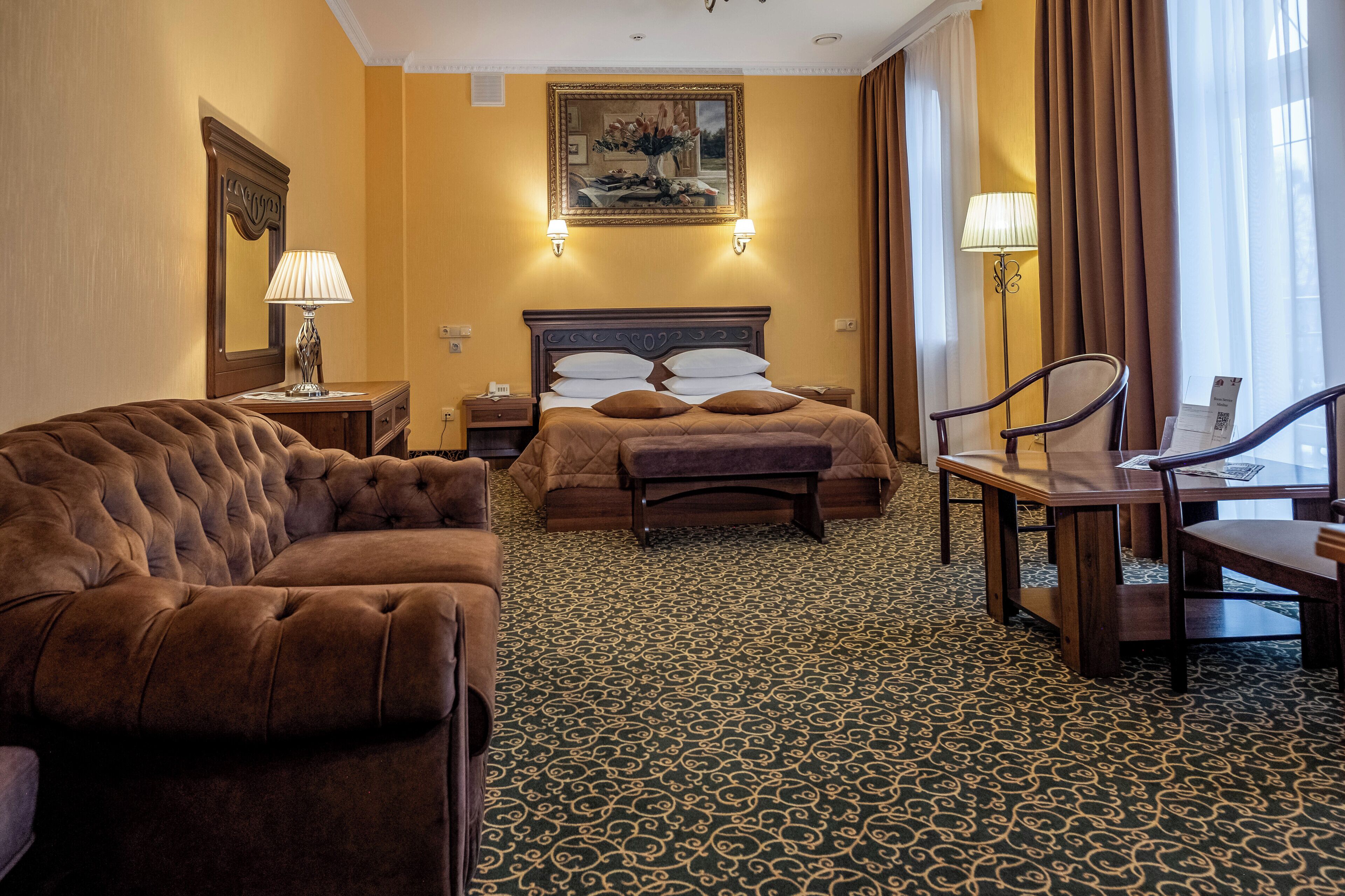 Ein Hotelzimmer mit einem großen Bett, einer Couch, einem Schreibtisch und einem Sessel.