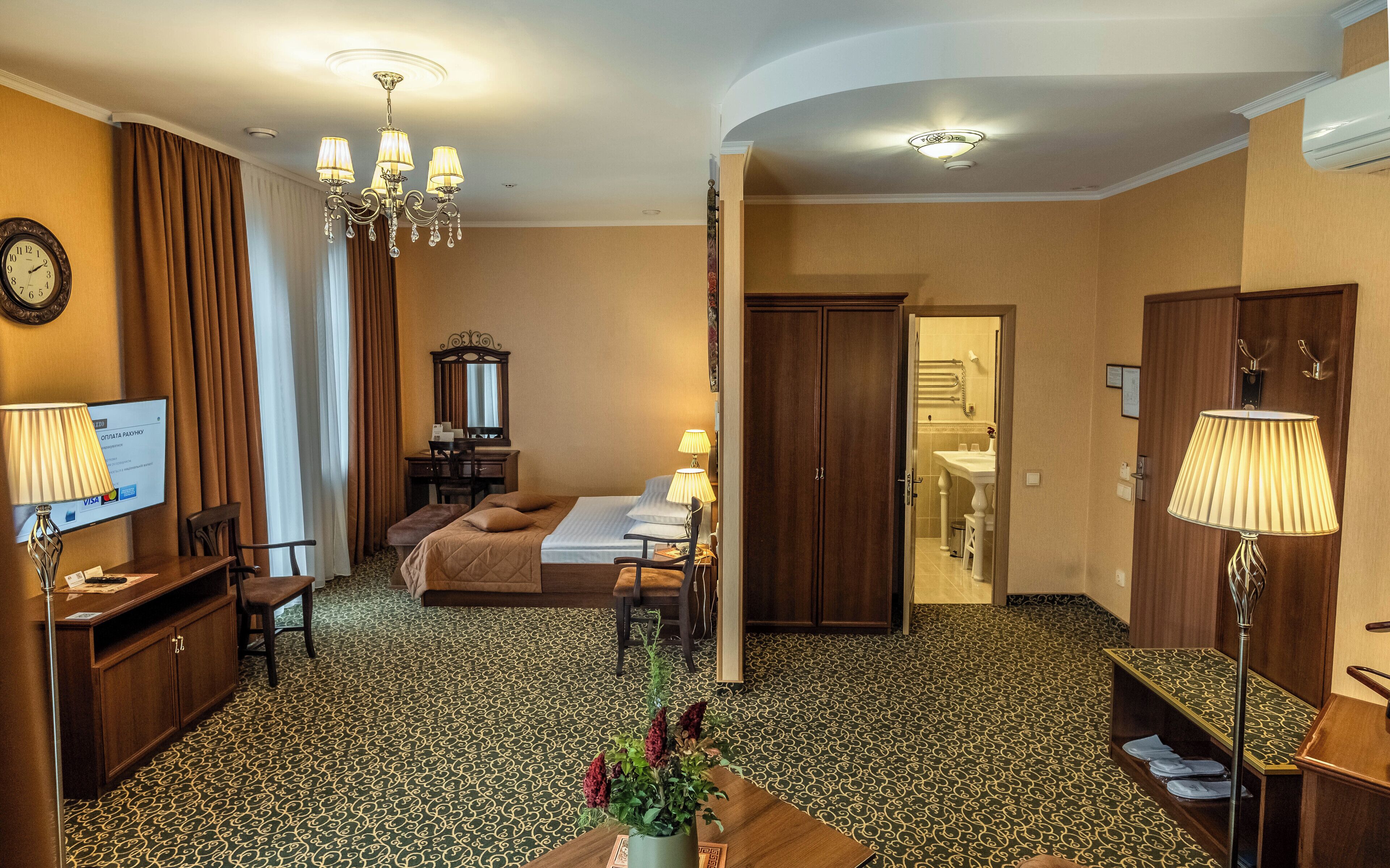 A hotel room with a bed, desk, chair, lamp, and a view of the bathroom.