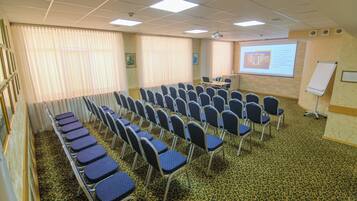 A conference room with rows of chairs, a projector screen, and a whiteboard.