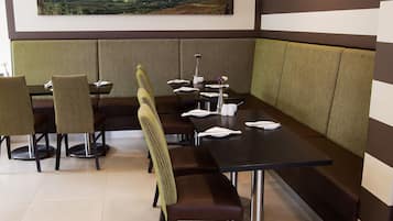 A restaurant with a long counter, booths, and a view of a landscape.