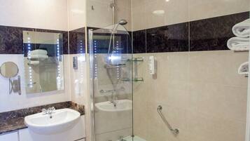 A modern bathroom with a glass-enclosed shower, a standalone bathtub, and a vanity with a sink.