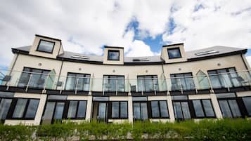 Un edificio moderno con varios balcones, ventanas amplias y una cubierta curva.