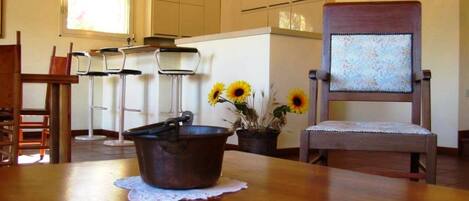 A kitchen with a wooden table, a chair, and a pot on the table.