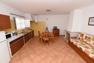 A compact kitchen with a dining table, chairs, a microwave, and a television.