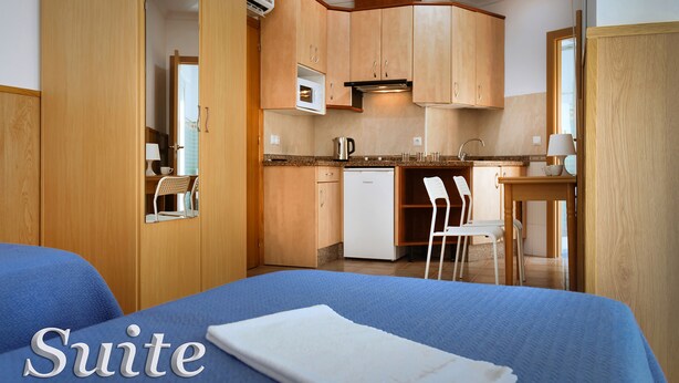Eine Hotel Suite mit Bett, einer Küchenzeile und einem kleinen Essbereich.