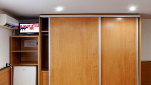Ein Zimmer mit Kleiderschrank, kleinem Kühlschrank und Wandfernseher.